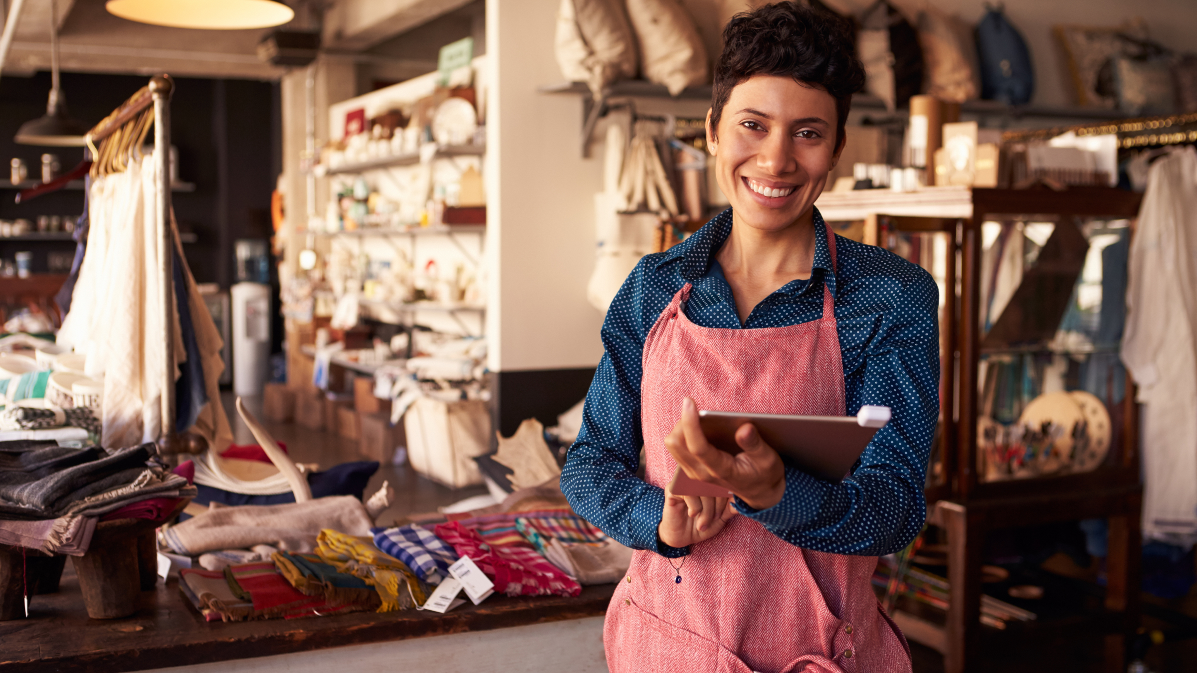 Self-employed worker in a shop using an iPad to manage digital tax records for MTD.