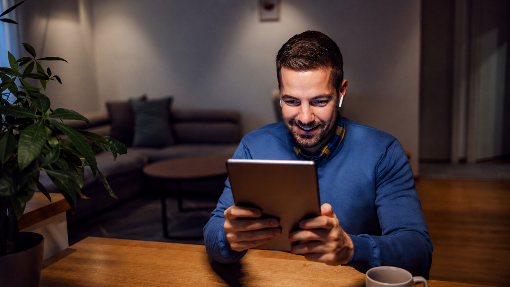 Self-employed professional working on a tablet at a wooden table in a modern home office during the evening, reviewing financial information and tax planning documents in a calm workspace.