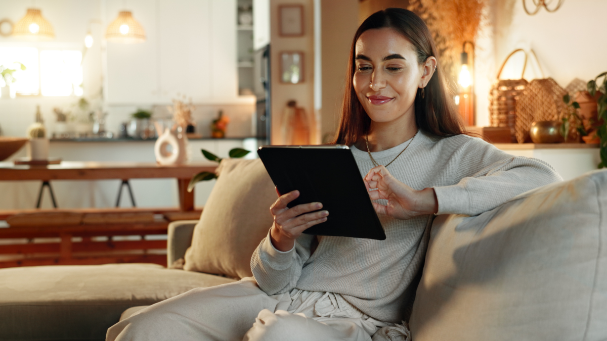 Woman using a tablet at home while reviewing business finances and planning her tax position during the tax year.