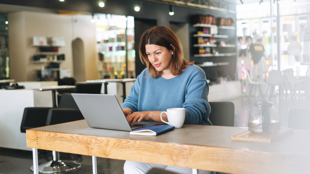 A small business owner works on a laptop in a modern café, reviewing digital financial records and preparing for their first Making Tax Digital quarterly submission.