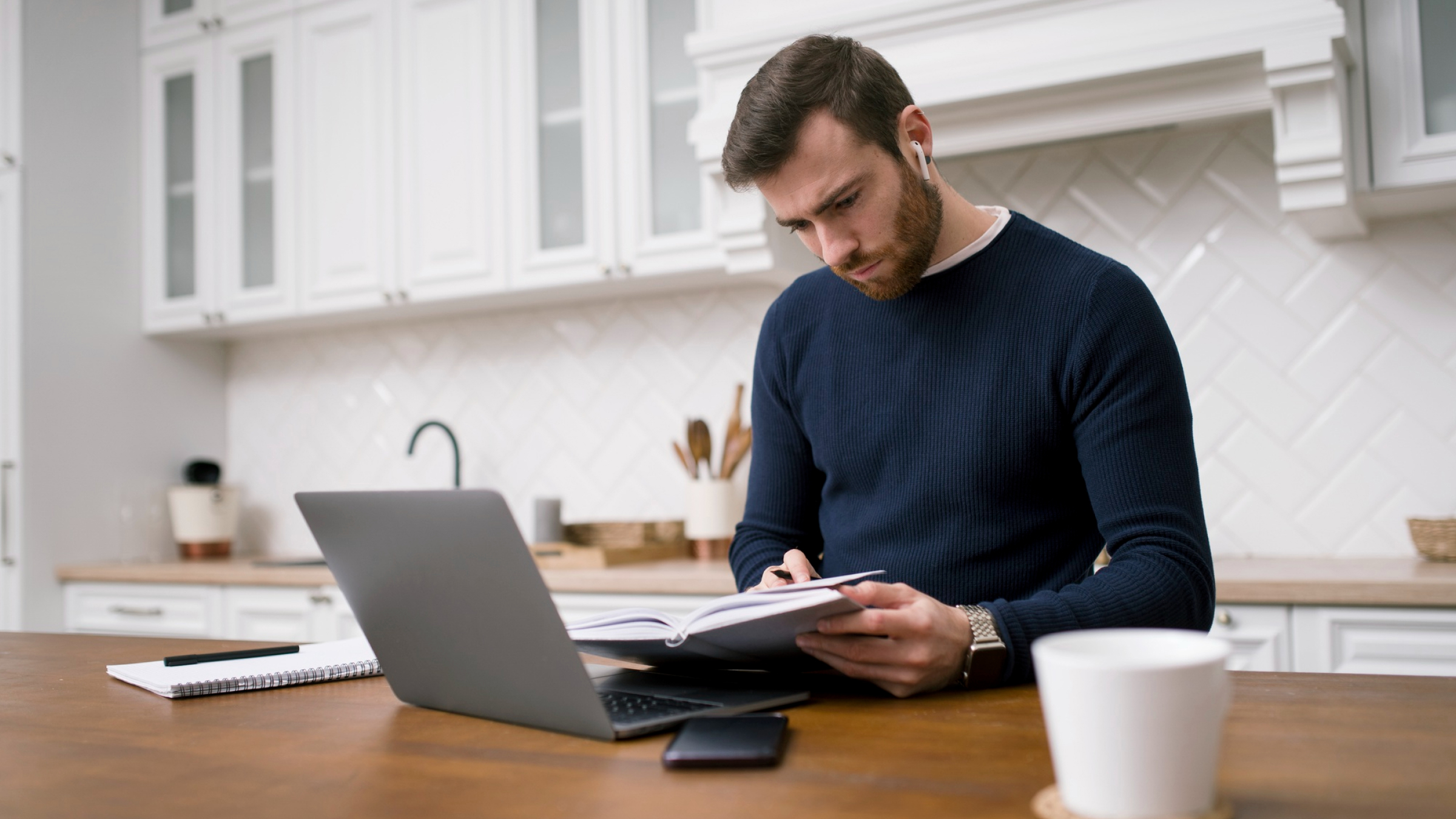 A self employed professional reviews business expenses and financial records beside a laptop at home.
