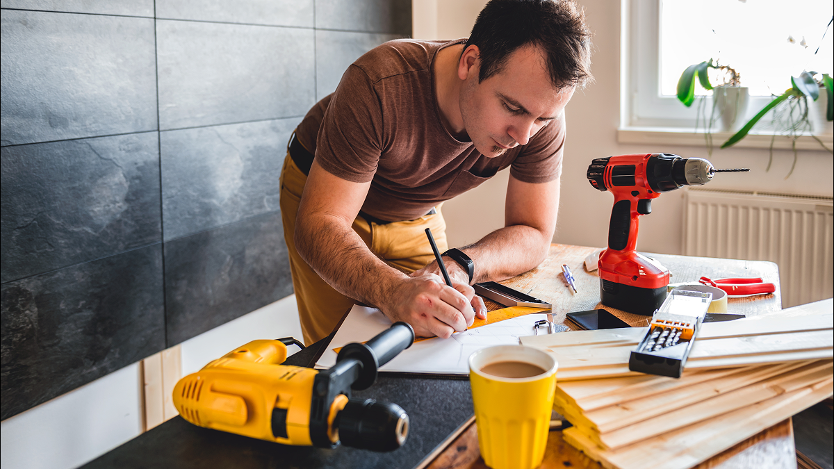 CIS subcontractor working at a construction workspace while reviewing plans and business records alongside tools and equipment.
